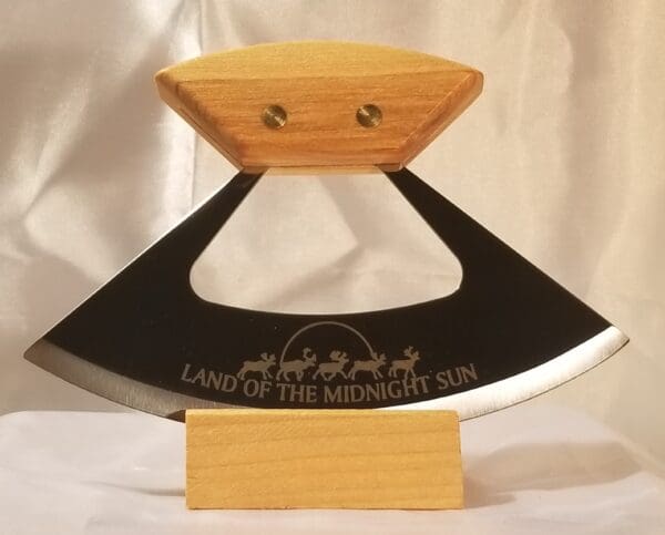 A wooden handle with a black blade and the words " land of the midnight sun ".
