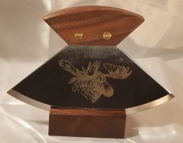 A moose with a 6" Alaskana Ulu's on top of a wooden base.