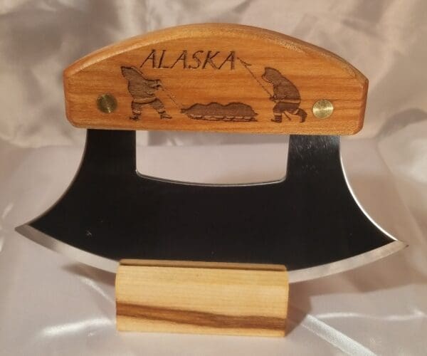 A wooden knife from the Inupiat Heritage Collection with the word alaska on it.