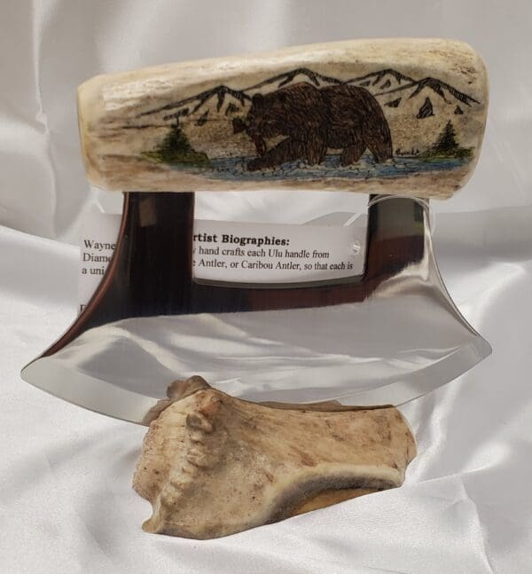 A bear and mountain scene on the side of a bone.