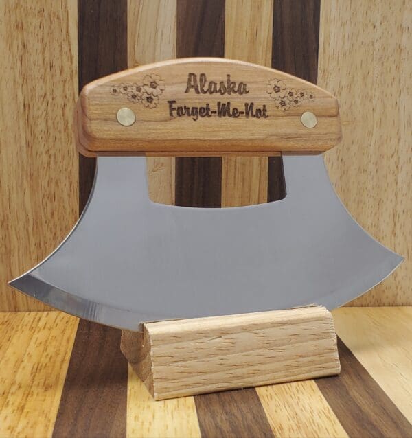 A wooden handle with an ulu knife on it.
