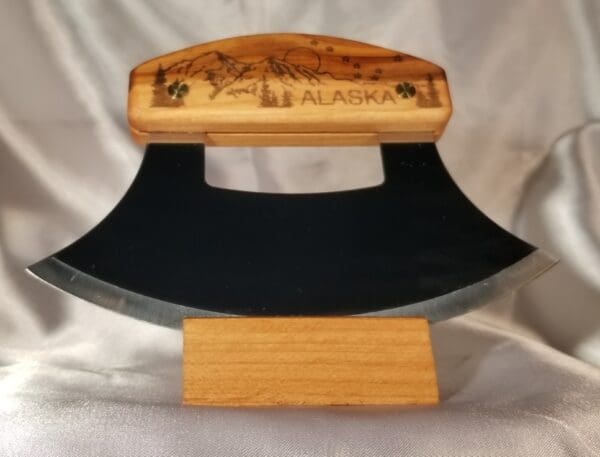 A wooden display with an ulu knife on top of it.