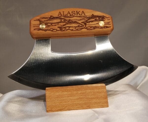 A ulu knife with an engraved alaskan design on it.