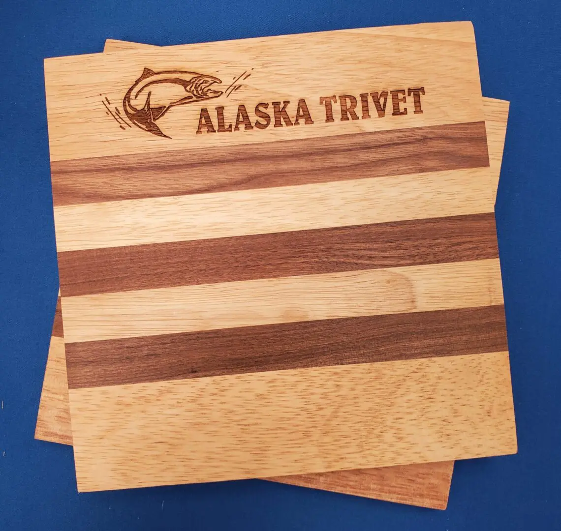 A wooden cutting board with the word Alaskan Trivet on it.