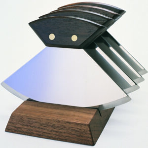 A wooden knife block with five knives on top of it.