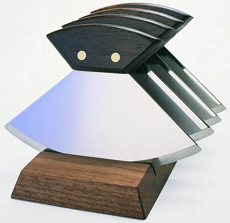 A wooden knife block with five knives on top of it.