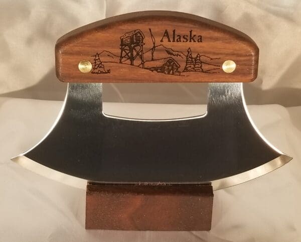 A wooden knife holder with an engraved alaska scene.