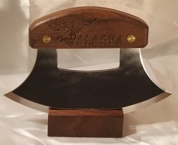 A wooden display with an ulu knife on it.