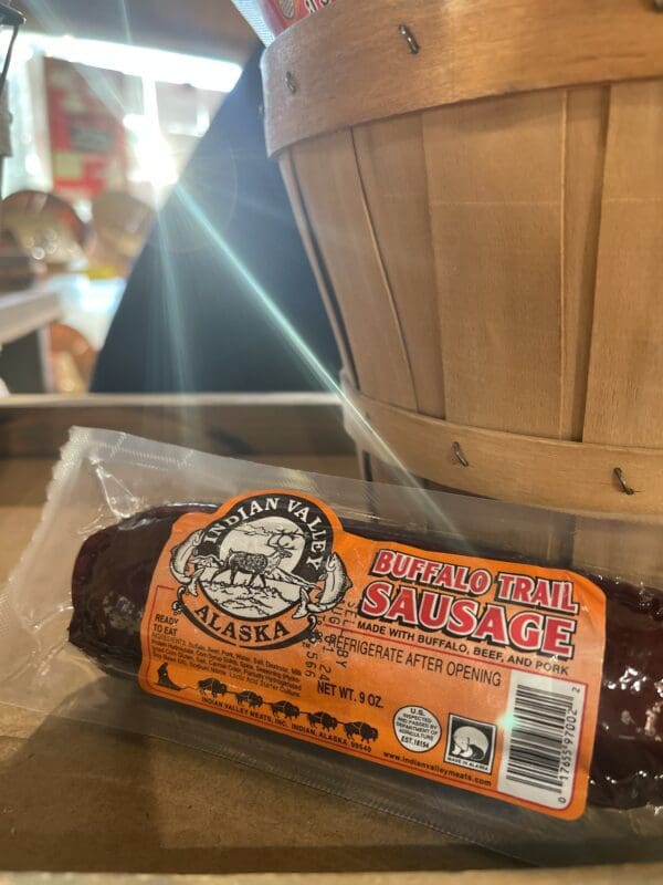 A package of sausage sits on a table next to a basket.